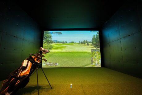Indoor golf simulator bay with clubs and a projected course