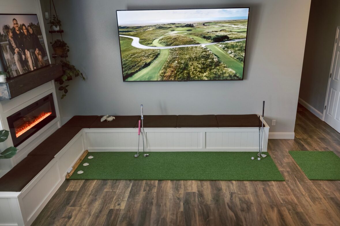 Indoor golf practice area with a putting mat and virtual course display