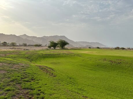 Green golf course surrounded by a mountainous desert landscape