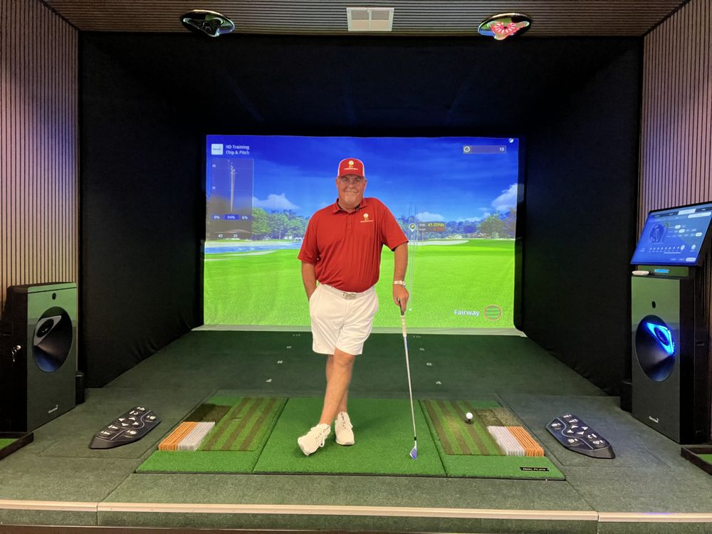 Golfer holding a club in a simulator bay at 24 Precision Golf